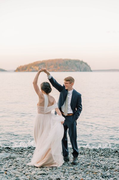 Romantic couple dancing on the rocky shores of Acadia National Park in Maine during their wedding day. The beautiful backdrop of the ocean and the couple's joyfully shared moment captures the essence of love and connection. Felisha, a destination wedding photographer based in New England, specializes in capturing intimate and timeless moments at weddings in Maine, New England, and worldwide locations.