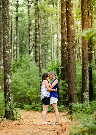 a couple embracing forehead to forehead in the forest