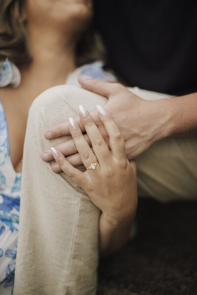 Close-up of couple holding hands gently on knee, capturing an intimate and emotional engagement moment