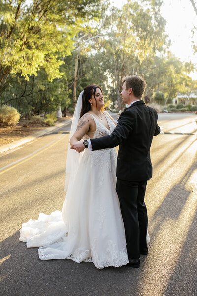 Bride and groom laughing as their bridal party rushes in for a joyful group hug, creating a fun and candid moment captured by a Bendigo Wedding photography professional.