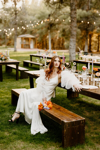 bride sits on bench at styled table