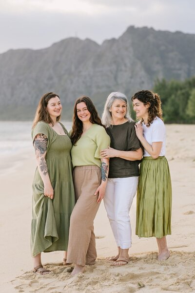 A mother stands with her three older daughters on the beach.