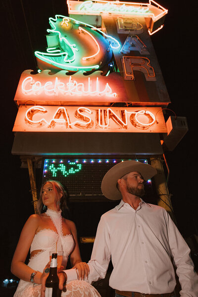 couple eloping in front of casino neon sign