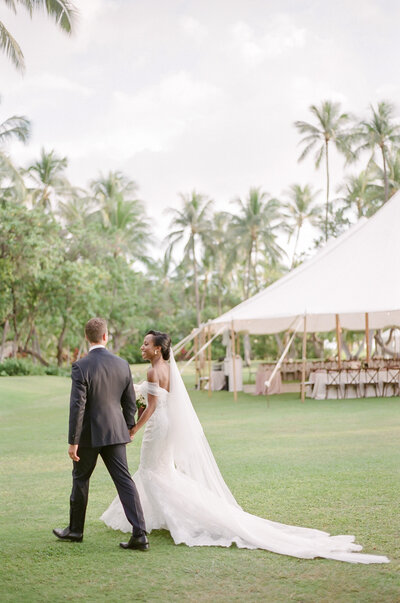 A black bride in a mermaid wedding dress exits their ceremony with her husband on Oahu.