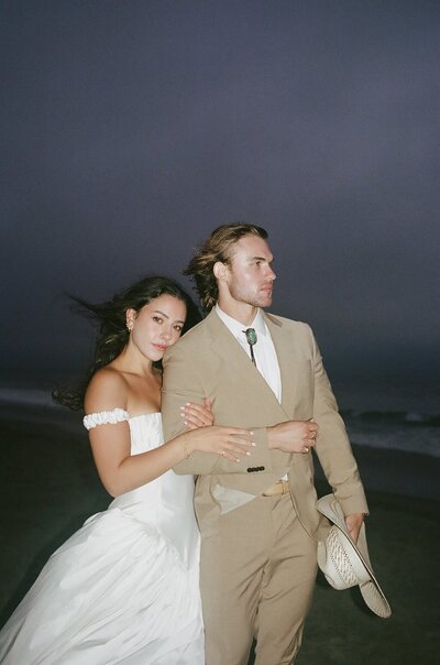 A couple stand on a cliff overlooking the Oregon Coast