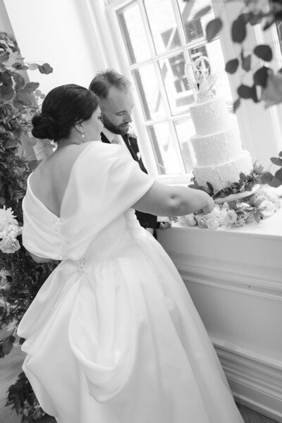 Black and white image of bride and groom cutting cake at intimate Nashville wedding