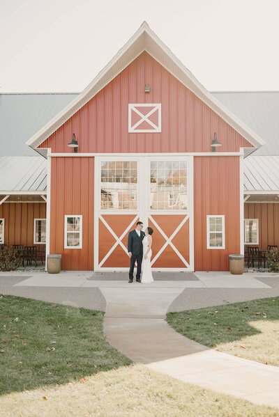 girl and man stand front of the red barn