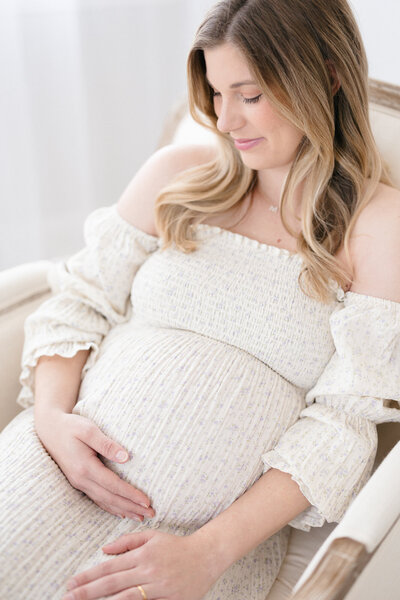 Portrait of an expecting mother wearing a nothing fits but dress in a bright Louisville maternity photography studio