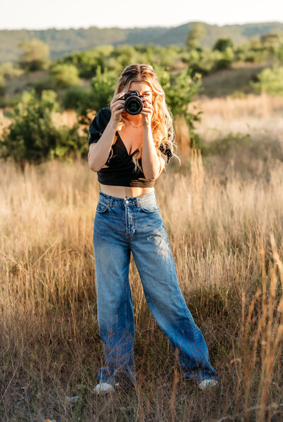 Family, Maternity & Newborn Photographer, Jessica Rockowitz walks down a country road with her camera in hand at golden hour
