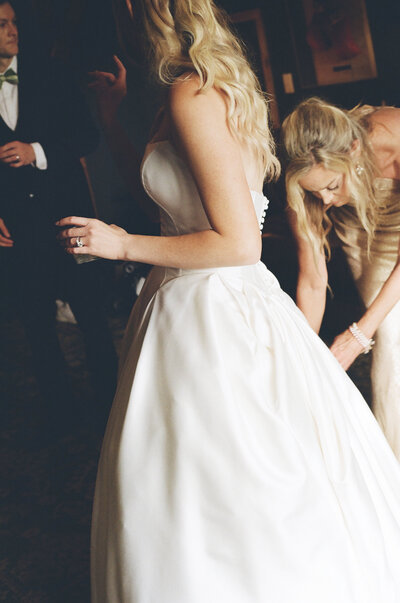 Film photo of bridesmaid adjusting bride's dress at Nashville wedding