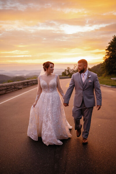 bride and groom holding hands and walking down the Foothills Parkway road and smiling at one another