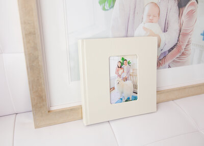 A cream leather album next to a golden framed family photo