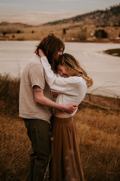 A couple laughing and embracing by Horsetooth Reservoir during the fall 