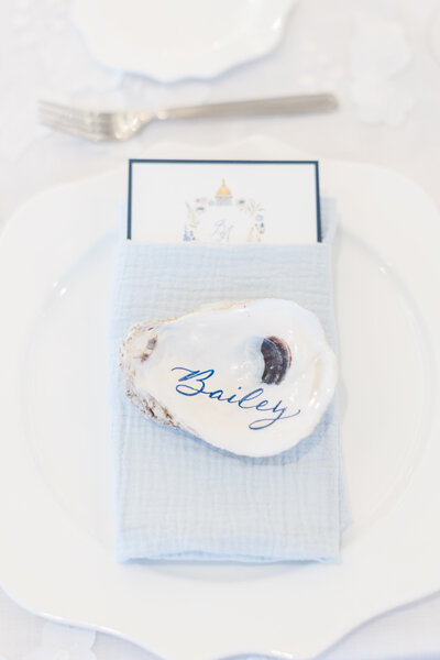 Oyster shell place card with calligraphy on light blue napkin for Cape Cod wedding at Wychmere Beach Club