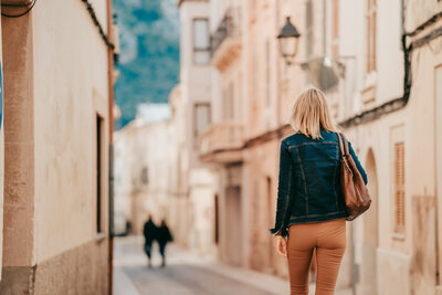 Sylke von hinten durch die Gasse einer Altstadt schlendernd
