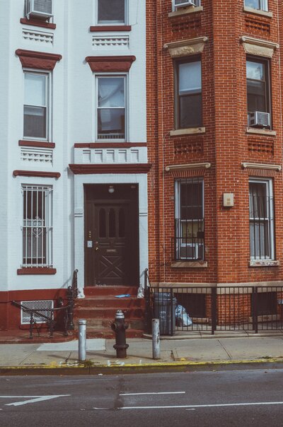Photo of a white and red-brick brownstone side by side.