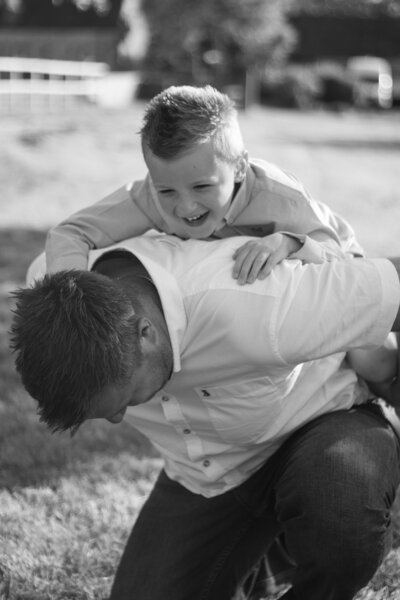 Son laughs as he climbs on his dads back