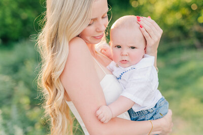 a close up of mom and son posing for a photo with her arms around him and the baby looking at the camera in lewiston idaho