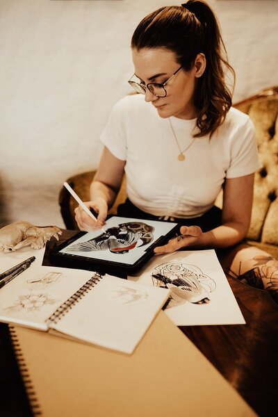 Beccsla Rebecca Knutson sitter och ritar tatuering på iPad.