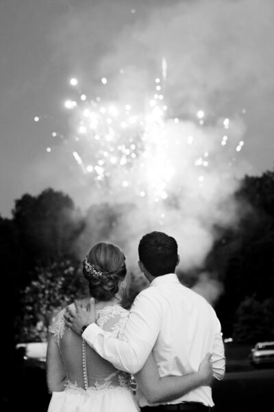 bride and groom hugs and embraces while taking in a surprise firework display during their intimate wedding reception. Aurora Ohio. Photo taken by Aaron Aldhizer