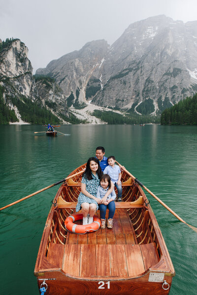 This captivating photo showcases a family rowing on a boat on the crystal-clear waters of Lago di Braies, a world-renowned lake nestled in the stunning Dolomiti Mountains of Italy. The image captures the family's joy and excitement as they explore the pristine beauty of this UNESCO World Heritage Site. The stunning scenery of the surrounding mountains and forests provides a breathtaking backdrop for this unforgettable moment on the tranquil lake