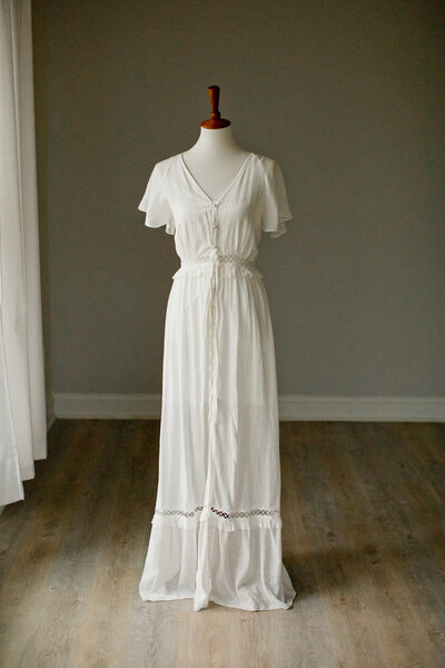 white dress with bell sleeves, buttons on the bust, and a peep window waist