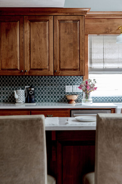 A kitchen with wooden cabinets and arabesque backsplash representing a farmhouse interior design by Winsome Home Interiors.