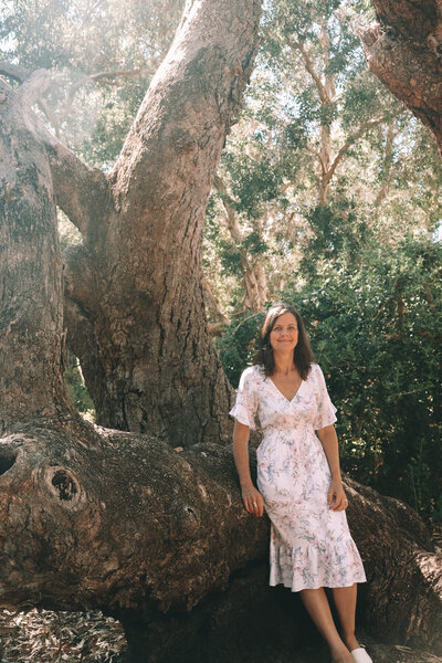 woman leaning against a tree