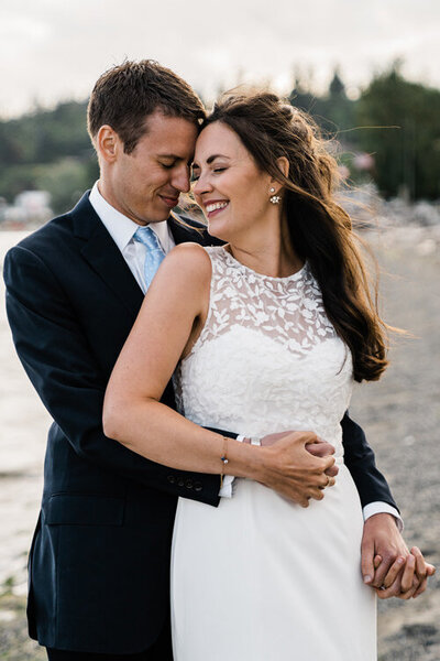 A bride and groom laugh together on a beach on Camano Island after their elopement