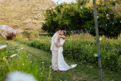 A bride and groom share a romantic kiss in a beautiful field of flowers at Lyons Farmette in Lyons, Colorado, during their summer wedding.