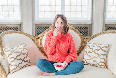 woman sitting on a couch eating candy