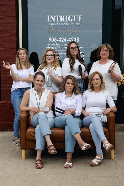 Group photo of hairstylists and beauty specialists at Intrigue Salon in front of their salon at 519.