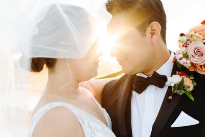 Bride and groom touching foreheads with them both under the veil