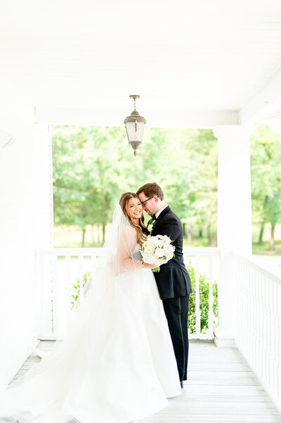 Bride and groom snuggle on porch