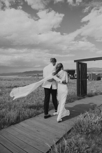 bride and groom walking down pathway with arms around each other