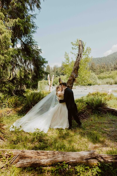 Adventurous bride wading through river in wedding dress during Washington elopemen