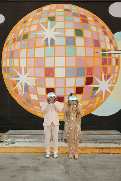 bride and groom holding disco balls