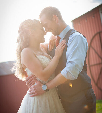 happy weddinhg couple lean foreheads together in front of sun