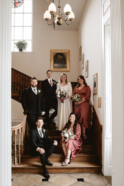 Bridge and groom with wedding party on stairs at the venue and laughing