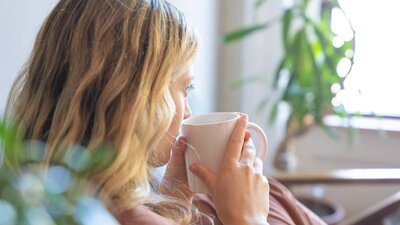 Kvinna sitter lugnt med en kopp kaffe – symbol för inre ro efter coaching mot medberoende