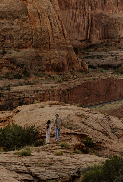 Couple Hiking and Holding Hands for their engagement photos In the Moab Desert in Utah