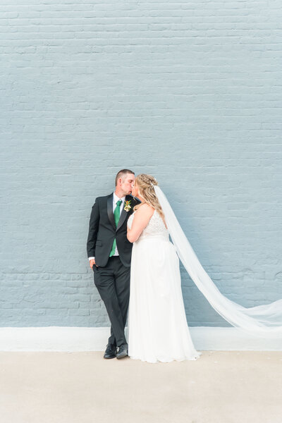 bride and groom hugging in field with giant viel