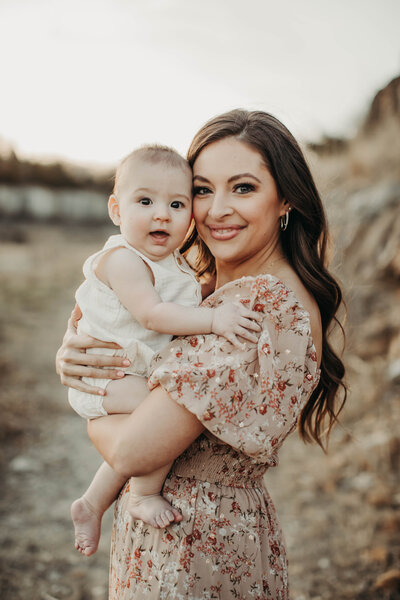 Mom smiling while holding her baby close during a family photo session.