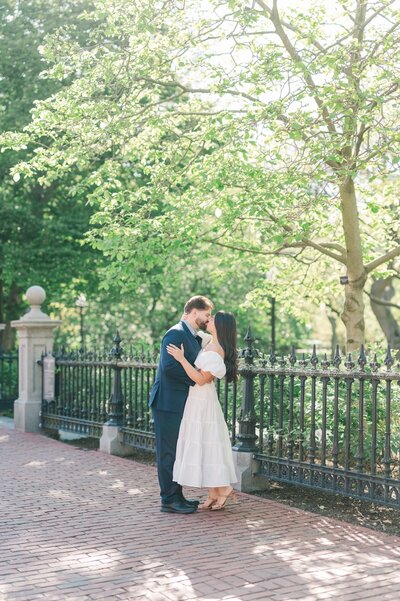 A woman and her fiancé kissing under a tree at Boston public Garden