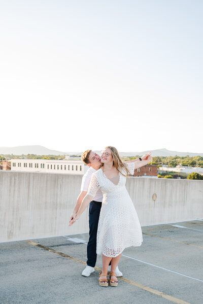 Woman leading her fiancé giggling and holding their arms out like an airplane