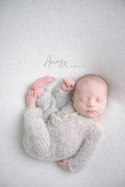 Newborn with teddy sleeping  in neutral wrap and bonnet in studio photography