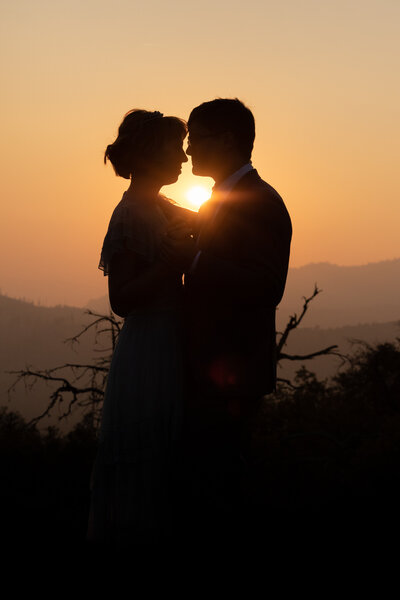 Bride and groom silhouettes in a smoky setting sun in Yosemite NP.