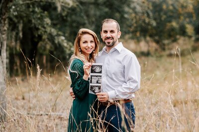 Mom and Dad to be in tall golden grass with sonogram near Orlando