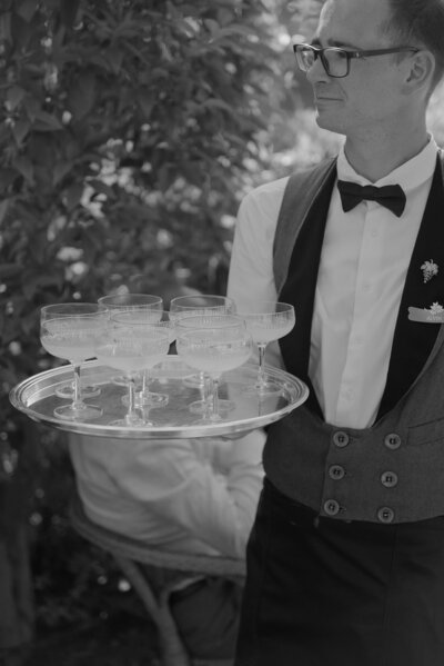 Black and white photo of a Bastide de Gordes wedding dinner featuring a long, rectangular table, soft candlelight and medieval architecture