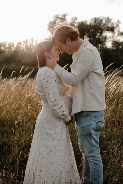een papa en een zwangere mama kijken naar elkaar. hun oudste kindje zit in de nek van de papa. de foto werd genomen tijdens een fotoshoot in Bonheiden.
